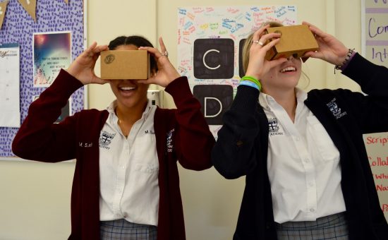 two teenage girls in school uniforms using Google Cardboard VR