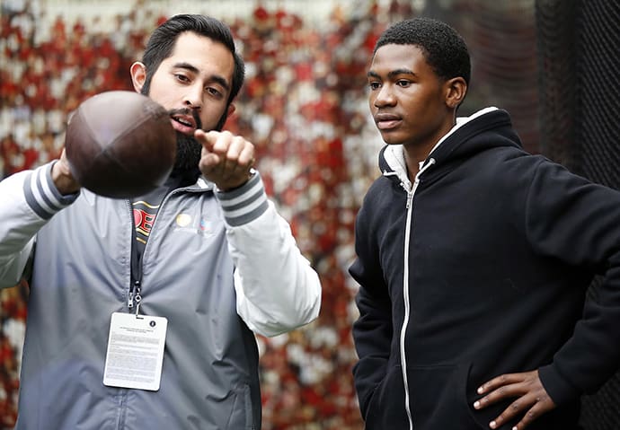 Josiah Rodriguez, left, educator at the 49ers Museum, explains the science behind a pass in the Chevron STEM Zone in Super Bowl City on Tuesday, Feb. 2, 2016 in San Francisco. The Chevron STEM Zone is an interactive exhibit that brings the science behind football to life for fans in Super Bowl City. (Tony Avelar/AP Images for Chevron)