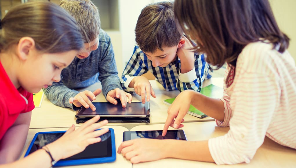 Students sitting around a table playing educational online games