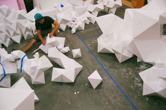 Student building large paper geometric shapes on cement floor