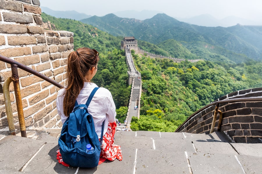 student with backpack sitting on great wall of china gazing at the horizon and experiencing deeper learning