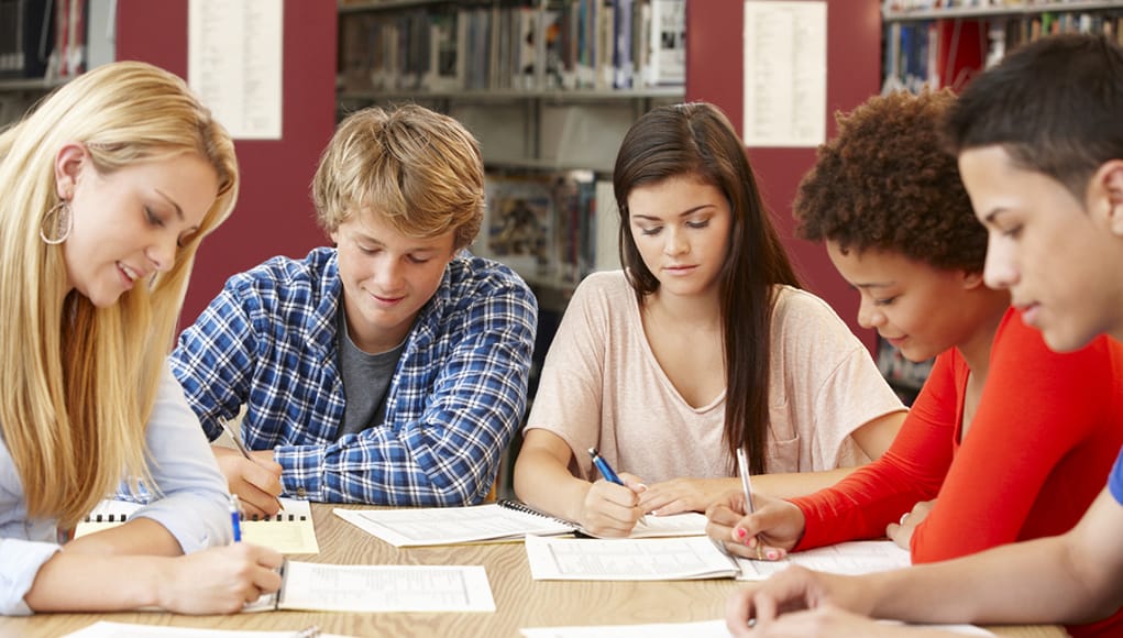 Five Students collaborating and working together on a project-based learning project in a library