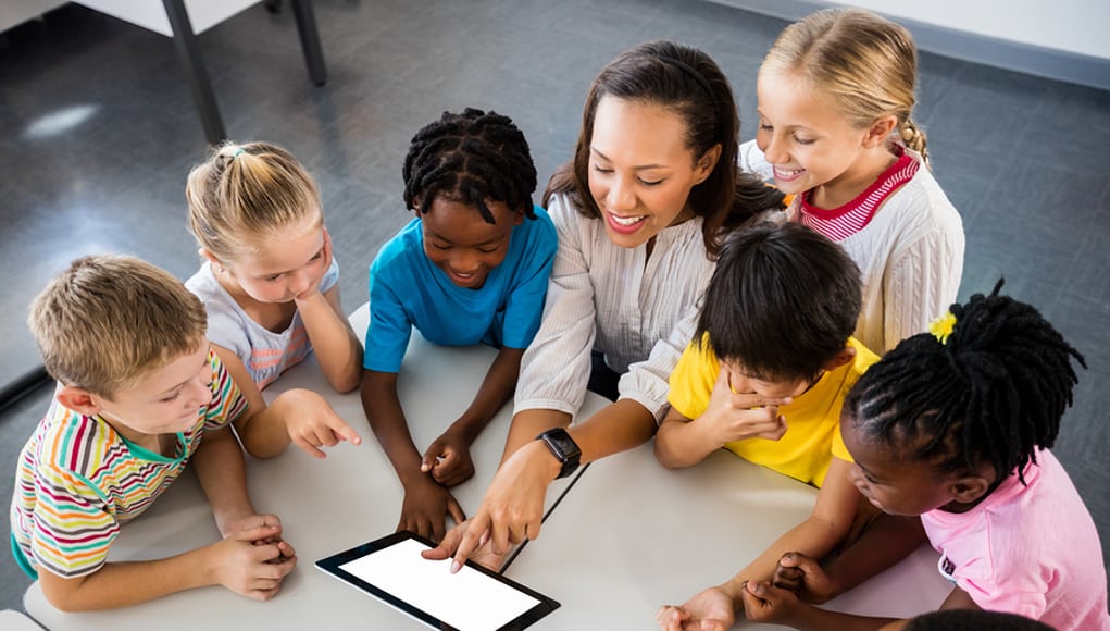 Teacher sitting around a table using one of the top apps for educators with her students