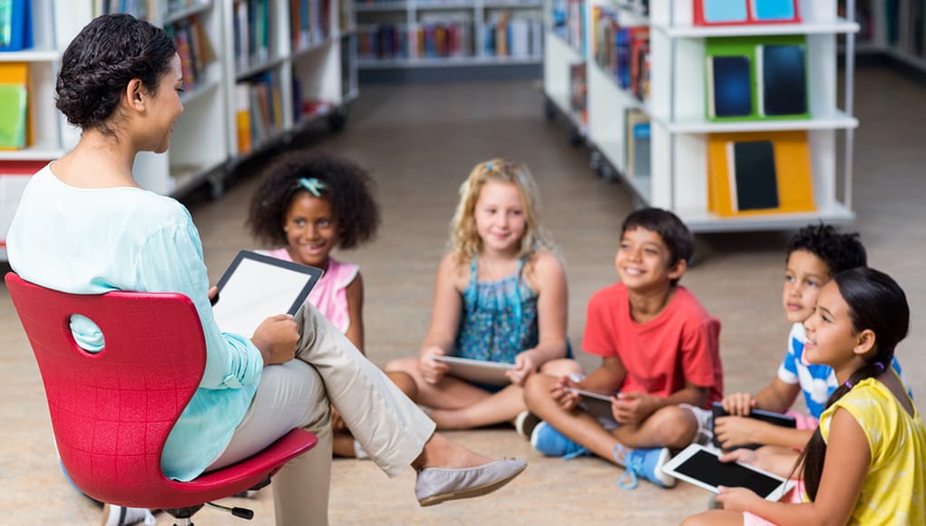 Teacher and young students with tablets using technology productively