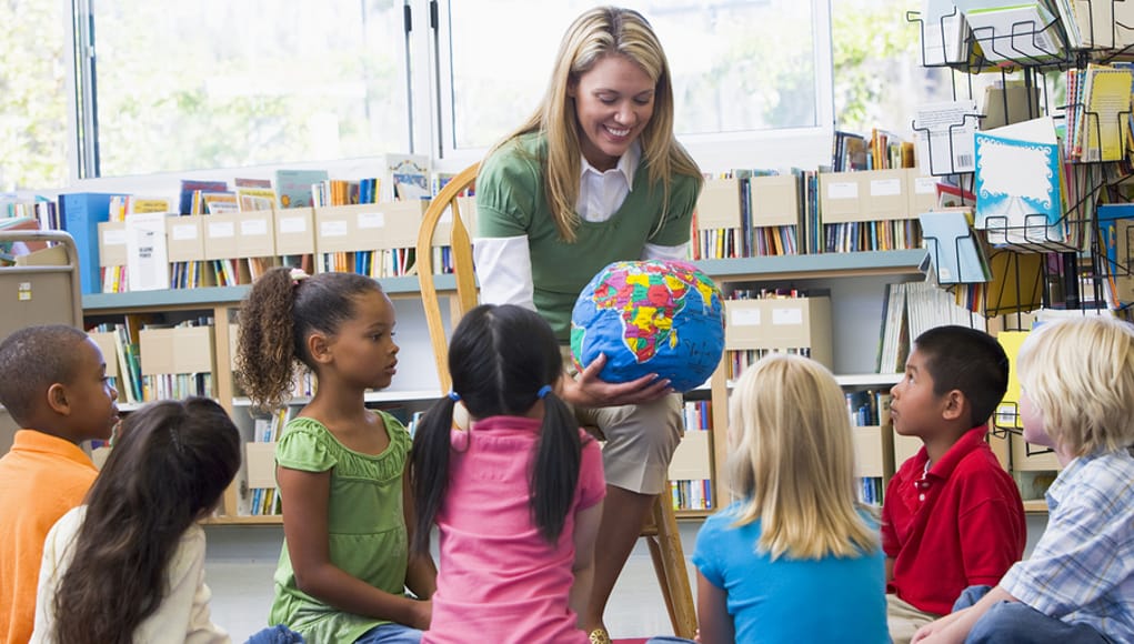 teacher showing students a globe to explain the globalized future of learning