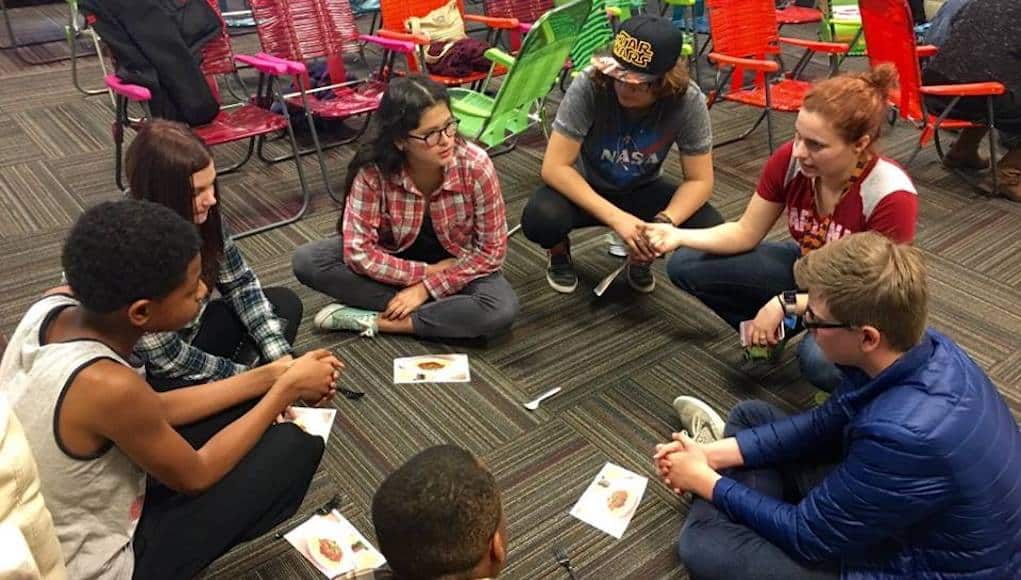 Students sitting on the floor talking at the denver school of innovation and sustainable design