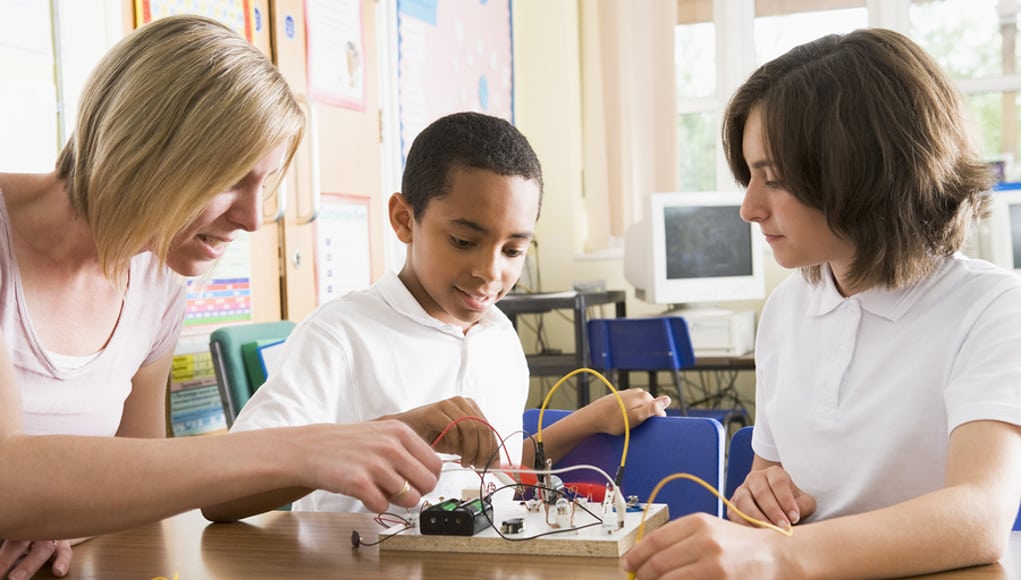 Teacher Helping Students with Project Feature Image
