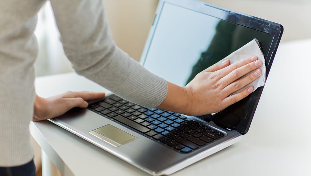 Person wiping dust off their computer so they can use their EdTech