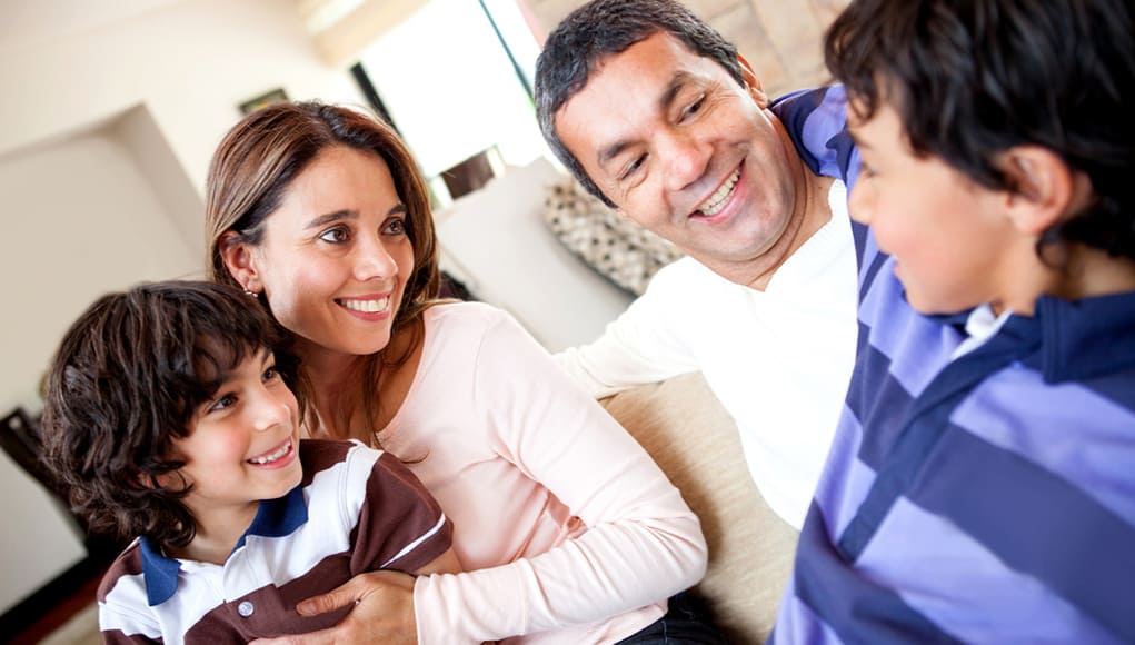 A family reading and smiling with their kids to help them learn