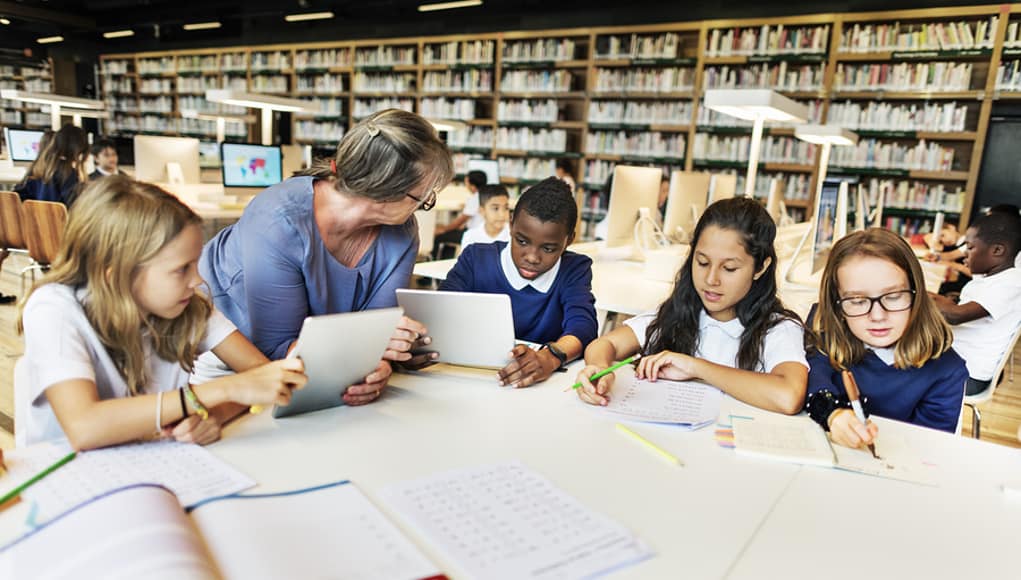 Teacher sitting at a table with students demonstrating good leadership