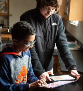 Two middle school boys work together on a coding project.