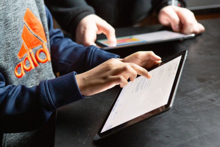 Students using tablets at a desk, exploring educational technology in a classroom setting