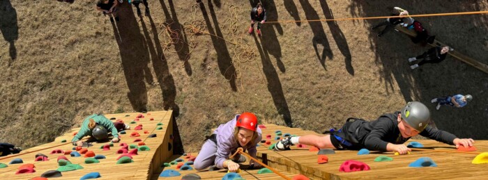 Student climb the rock wall at the adventure park.